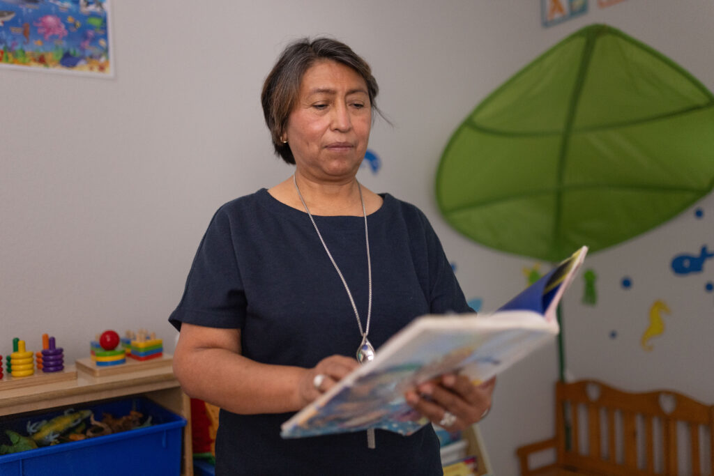 Rosi Paredes reads a book in her home daycare in Venus, Texas, surrounded by toys