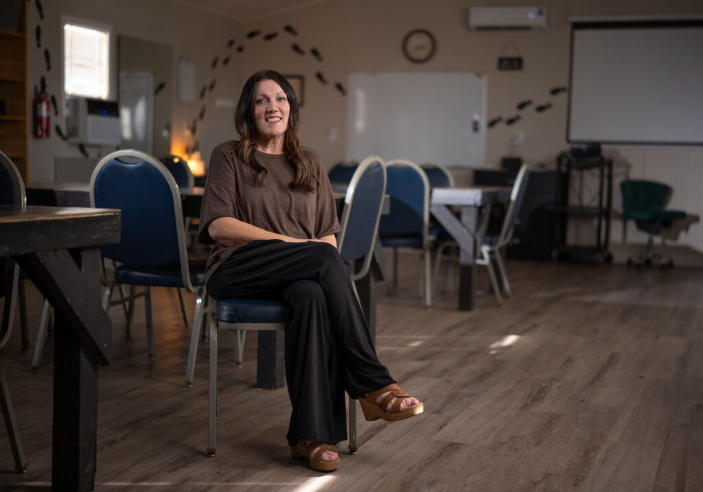 Woman sitting on a chair in an empty classroom with tables and chairs
