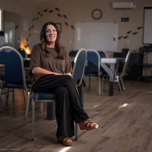 Woman sitting on a chair in an empty classroom with tables and chairs