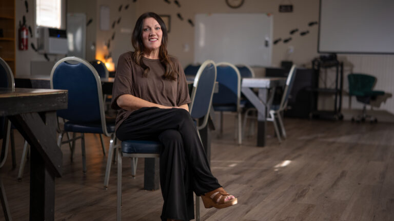 Woman sitting on a chair in an empty classroom with tables and chairs